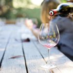 Iemand schenkt een glas rode wijn in